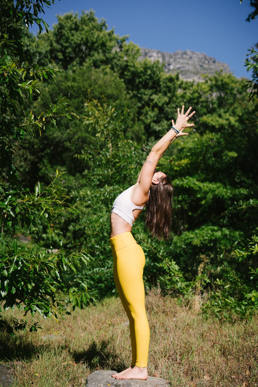 Woman practicing yoga outdoors with a serene natural background
